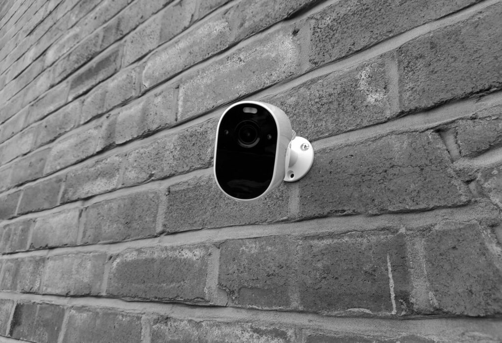 Monochrome Photo of a Surveillance Camera on a Brick Wall